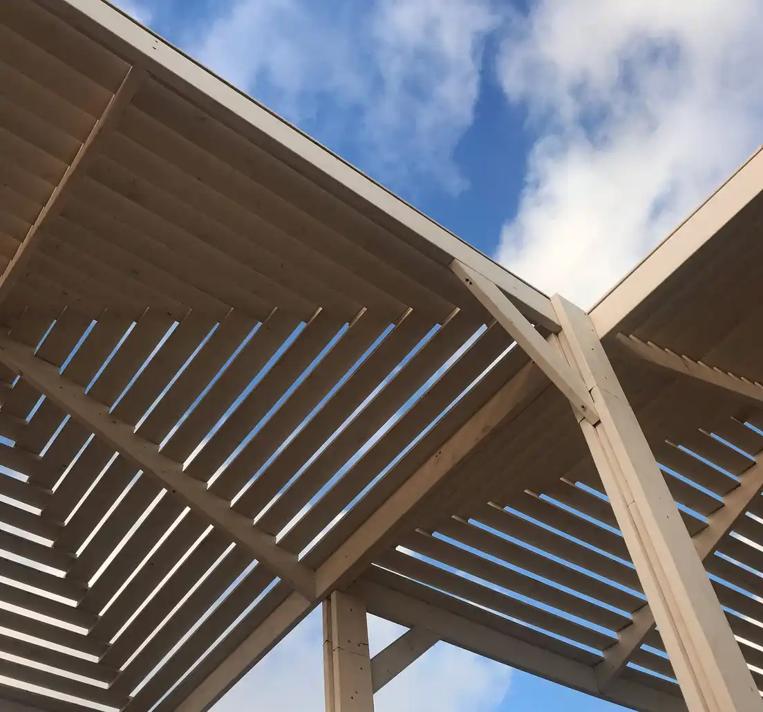 A close-up of a slatted louvered patio cover roof against the sky