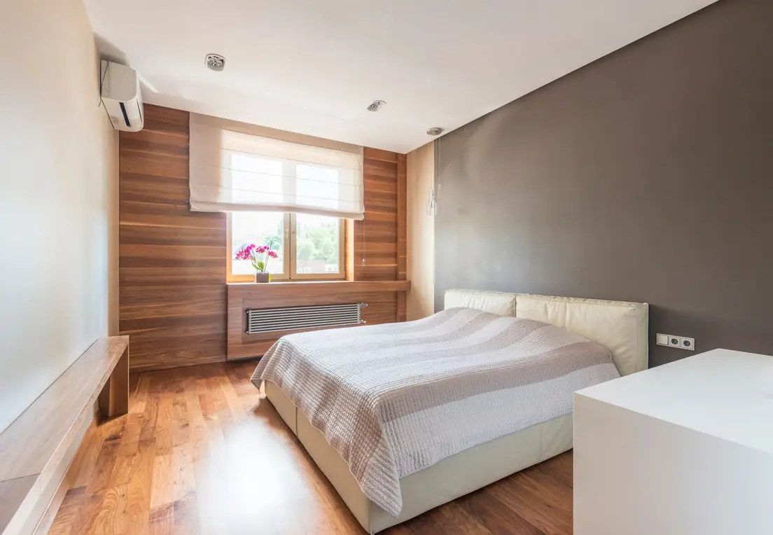 A low-profile upholstered platform bed with a storage base, wood panel wall, and charcoal accent wall