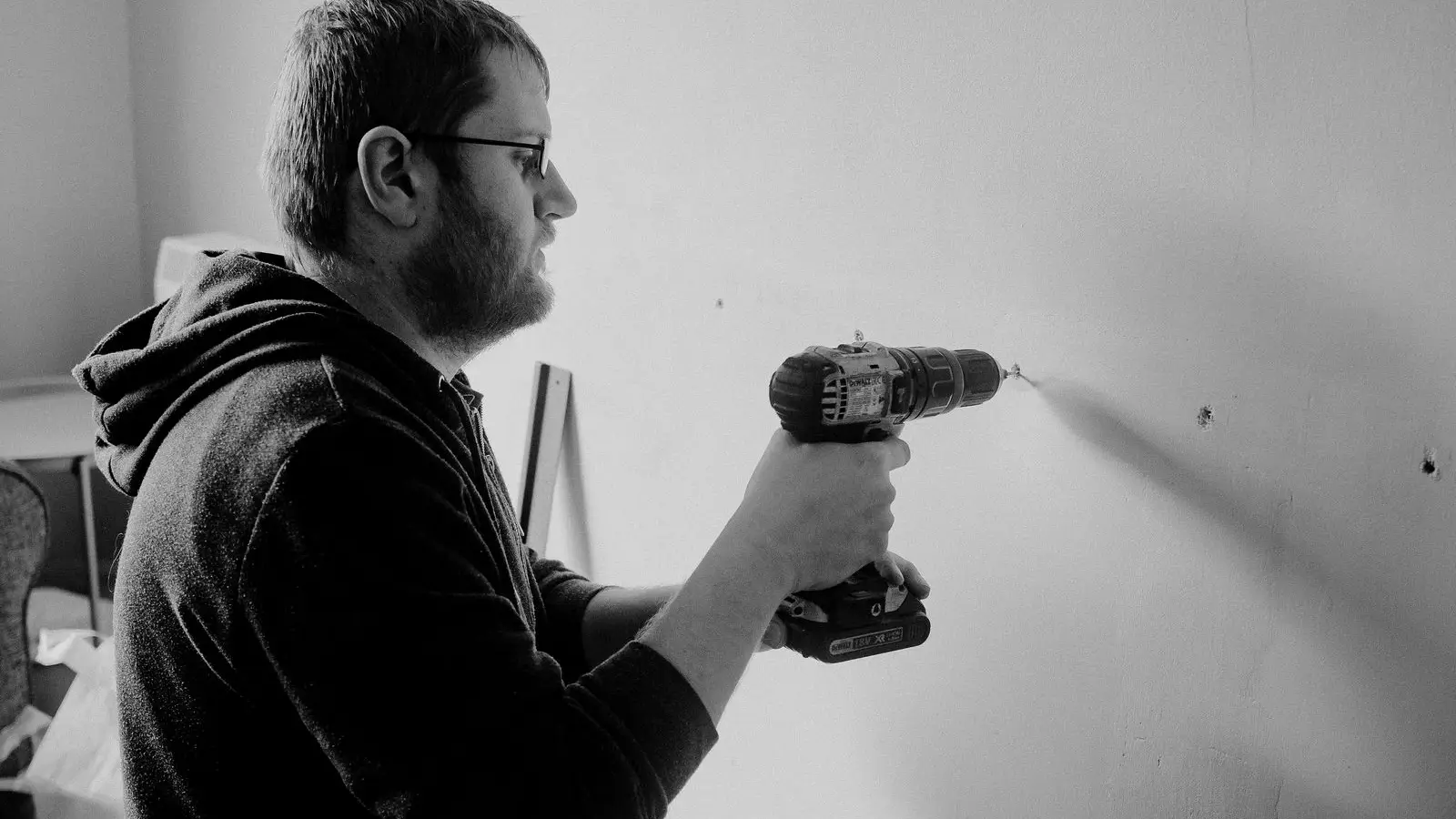 A person using a stud finder against a wall to locate ceiling joists before framing a temporary wall