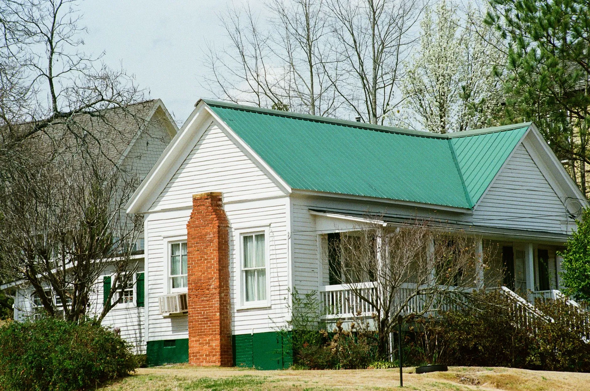A white farmhouse exterior with a standing-seam metal roof and a front porch