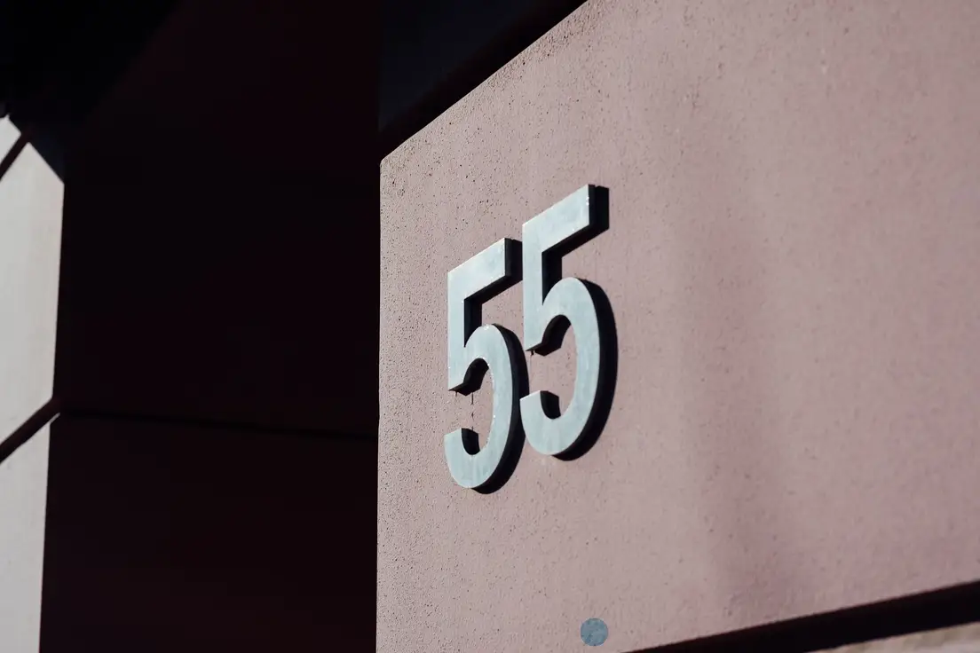 Brushed metal modern house numbers in a clean sans-serif font on a stucco wall, a mid-century curb appeal detail