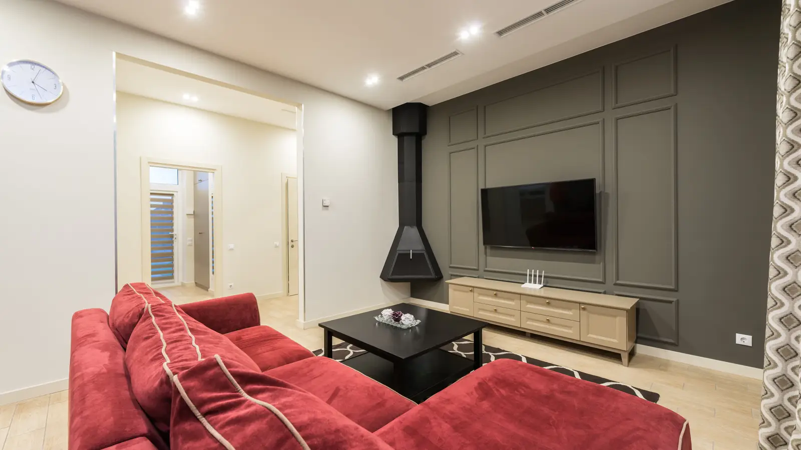 A wall-mounted TV centered on a dark gray wall with picture-frame wall molding panels