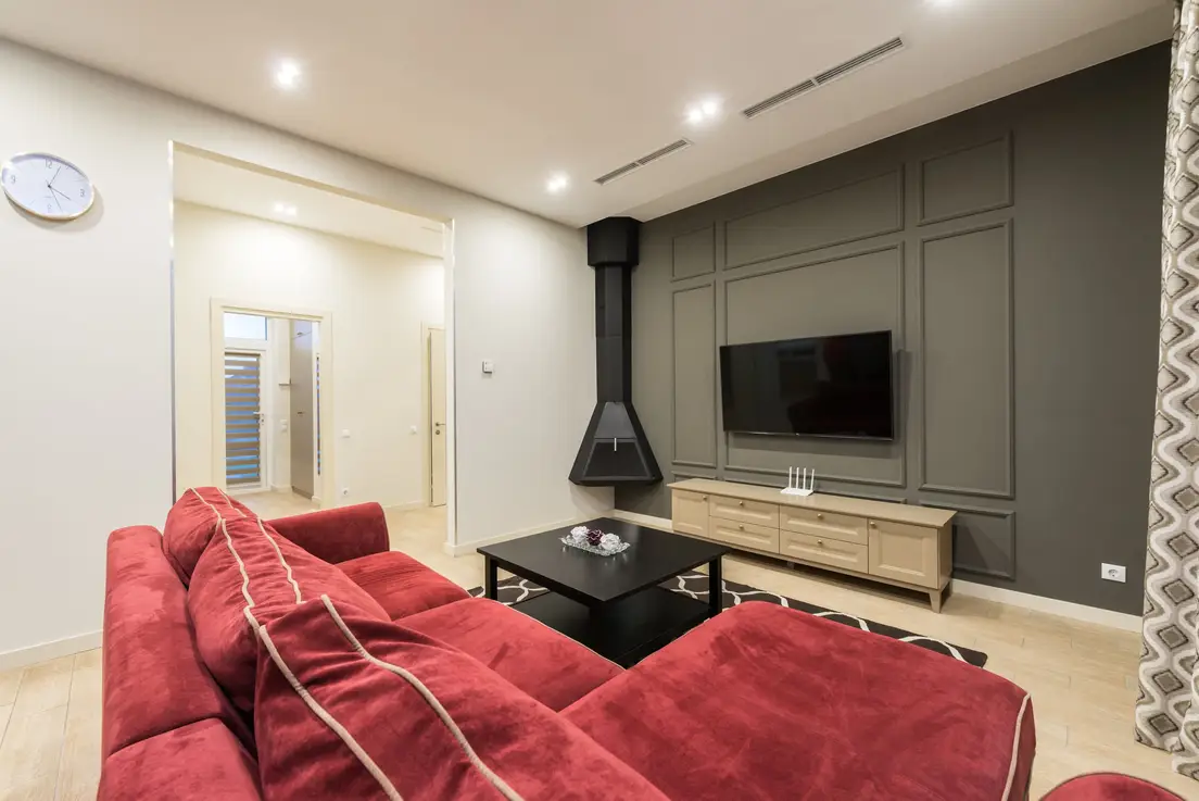 A wall-mounted TV centered on a dark gray wall with picture-frame wall molding panels