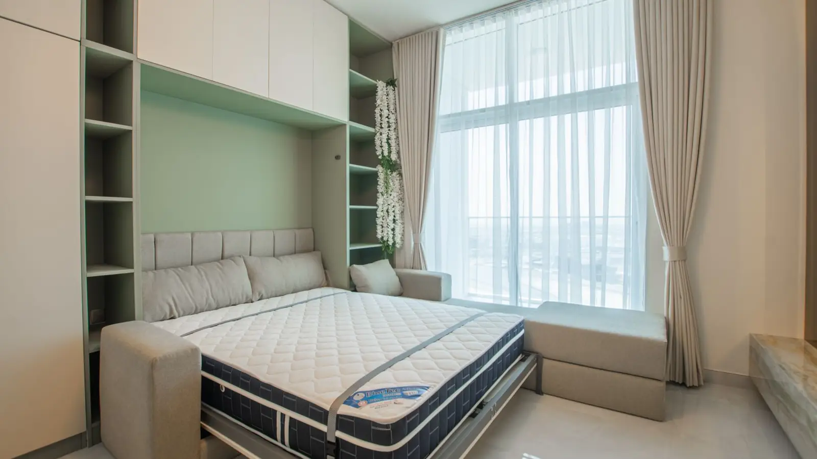A Murphy wall bed pulled down from built-in cabinetry in a small bedroom