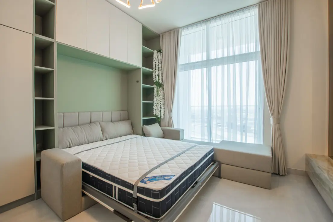 A Murphy wall bed pulled down from built-in cabinetry in a small bedroom