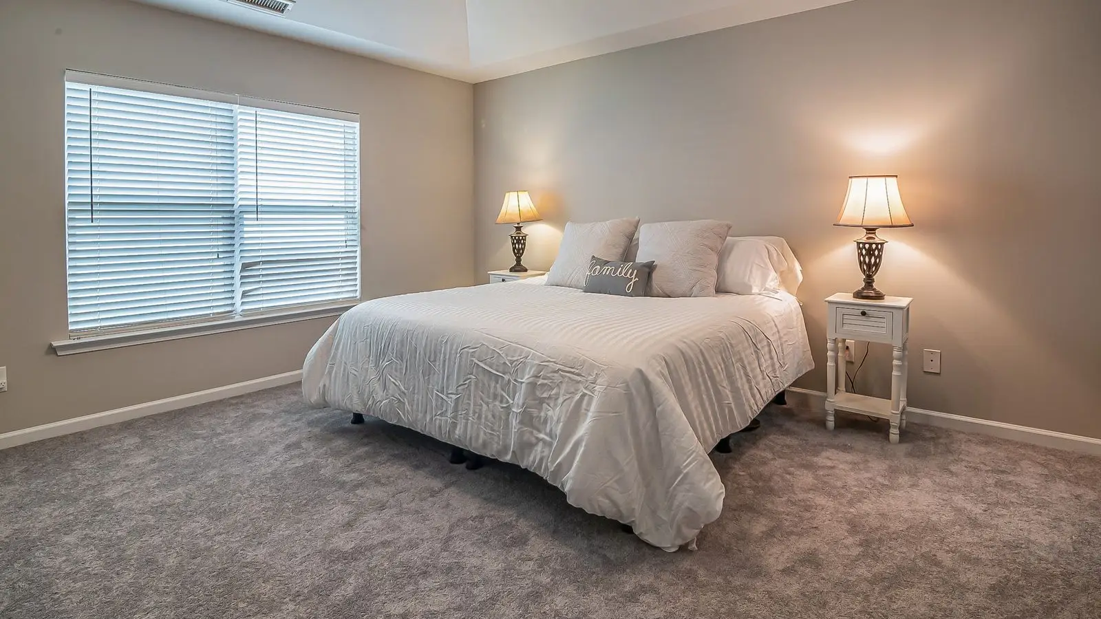 A pair of matching nightstands with lamps on either side of a bed