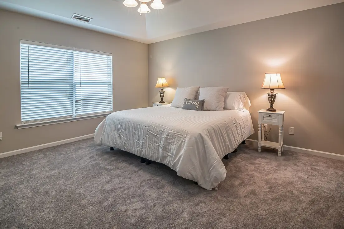 A pair of matching nightstands with lamps on either side of a bed