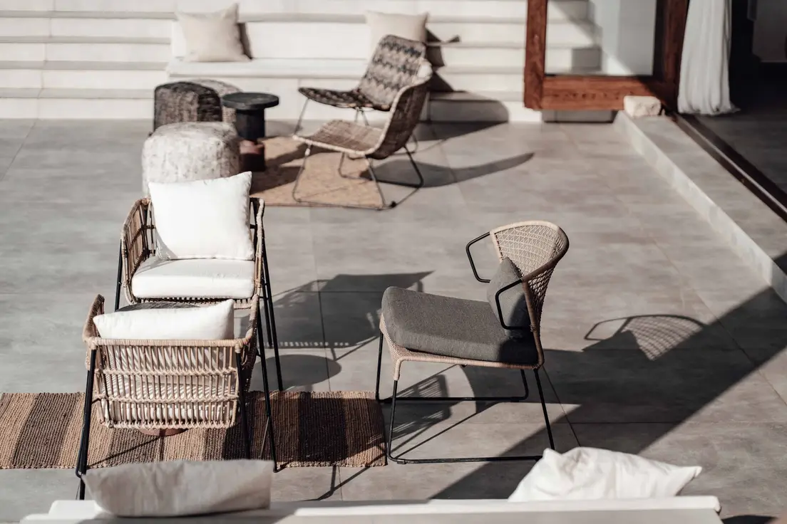 Rattan patio chairs layered with cushions and an outdoor rug