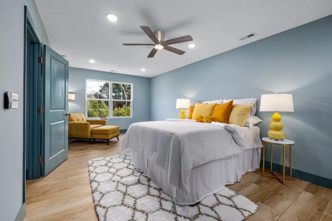 A bedroom with a bold blue accent wall and warm yellow bedding accents