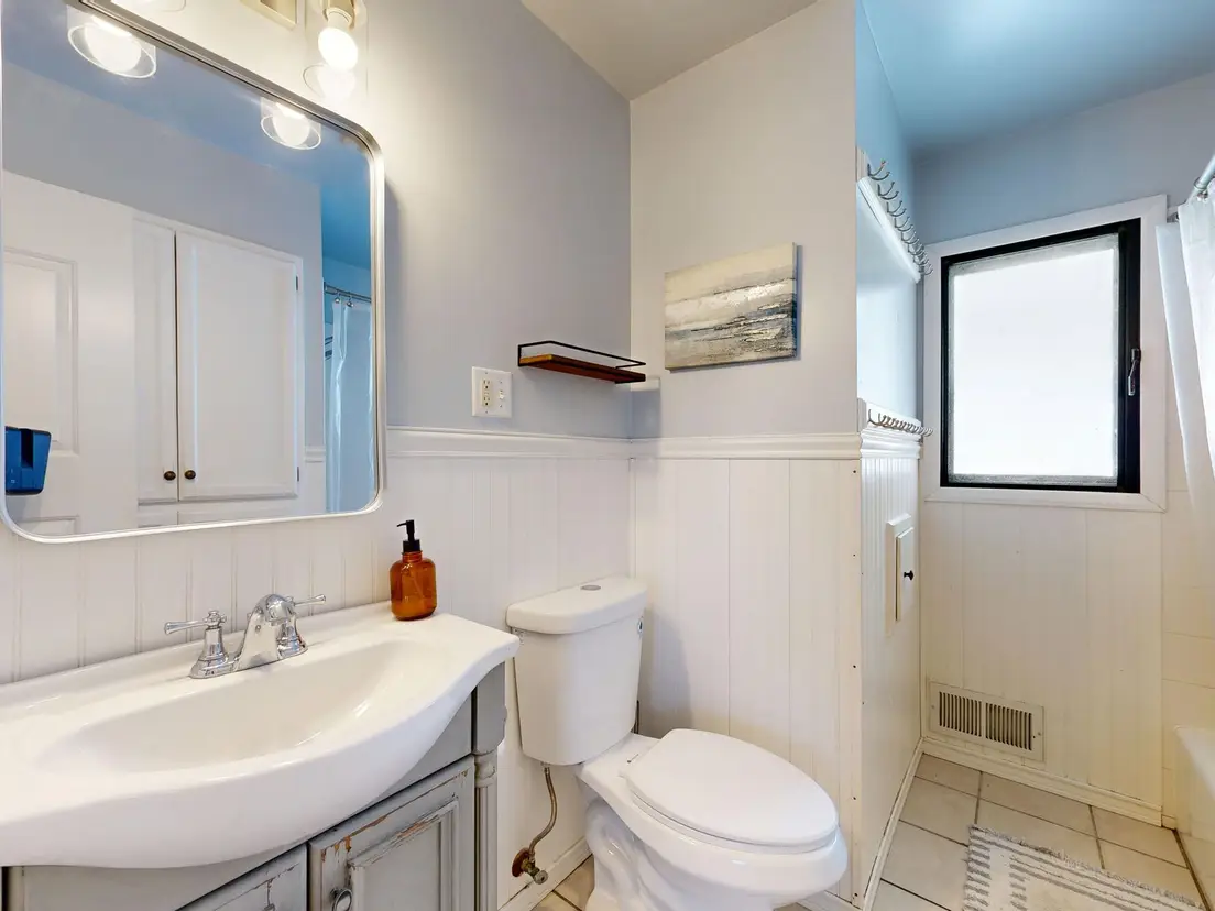 A small half bathroom with a pale blue painted ceiling and white walls