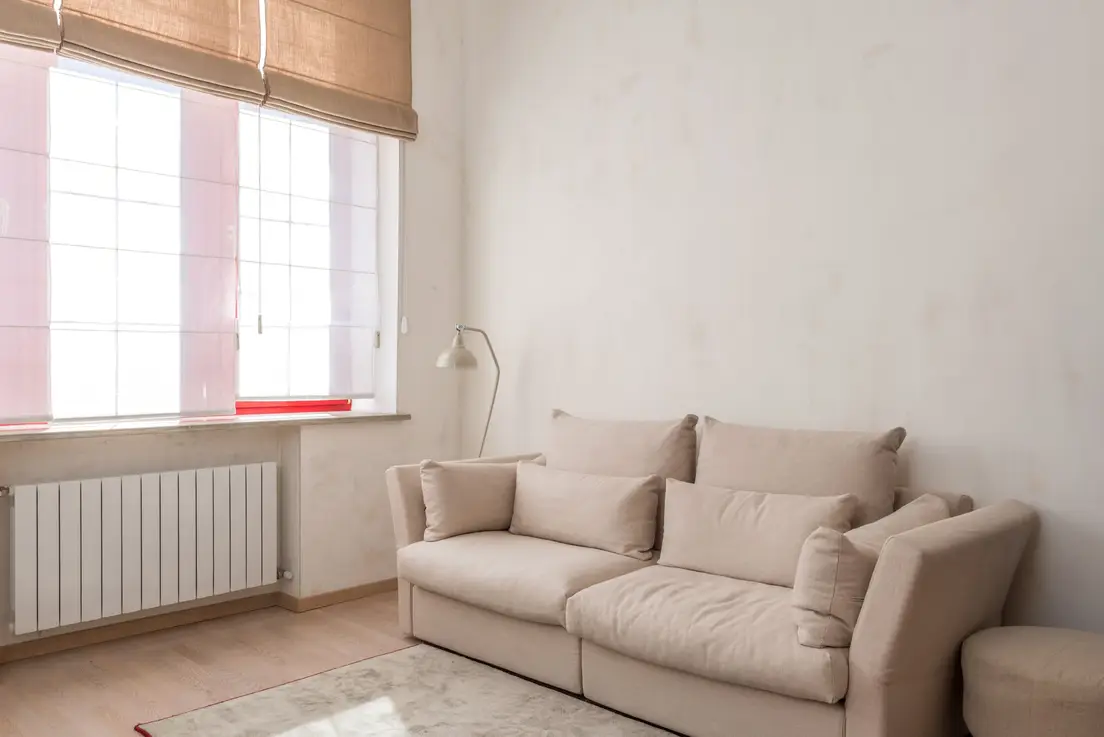 A warm beige minimalist living room wall with a linen sofa and natural afternoon light