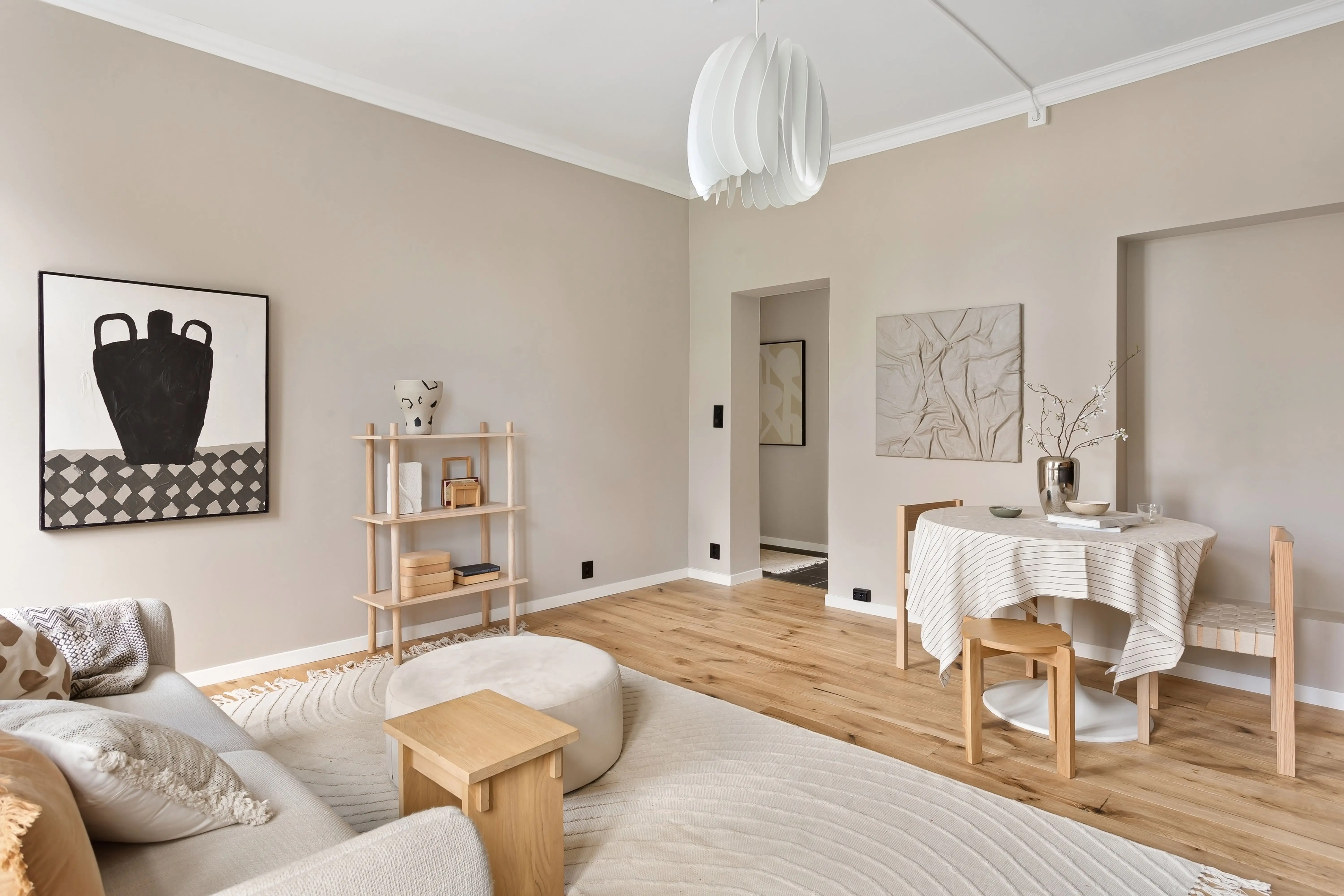 A beige minimalist living room wall in warm neutral tones with natural light and simple decor
