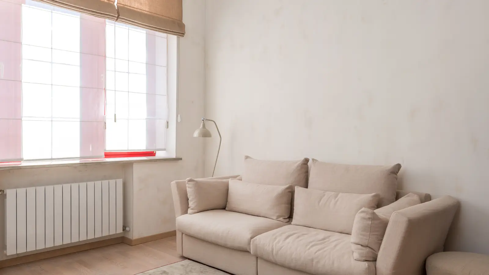 A warm beige minimalist living room wall with a linen sofa and natural afternoon light