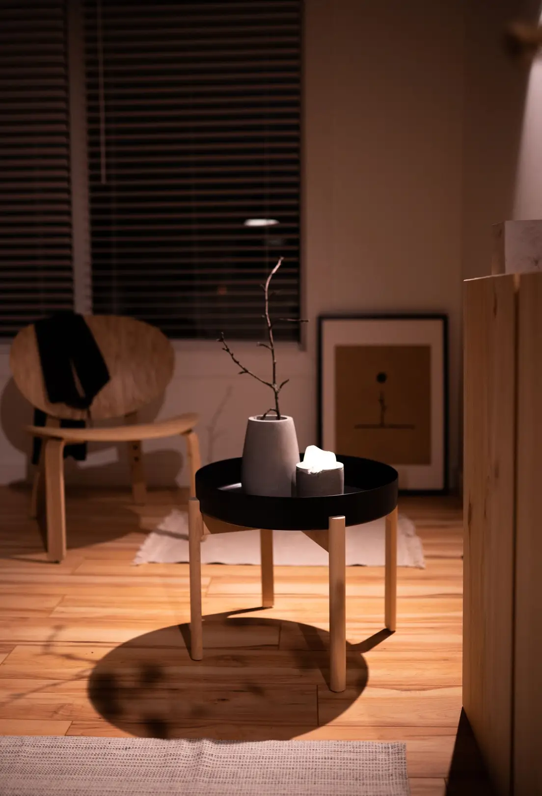 A warm japandi seating area with cane-back chairs, a plaster side table, and dried botanicals against neutral curtains
