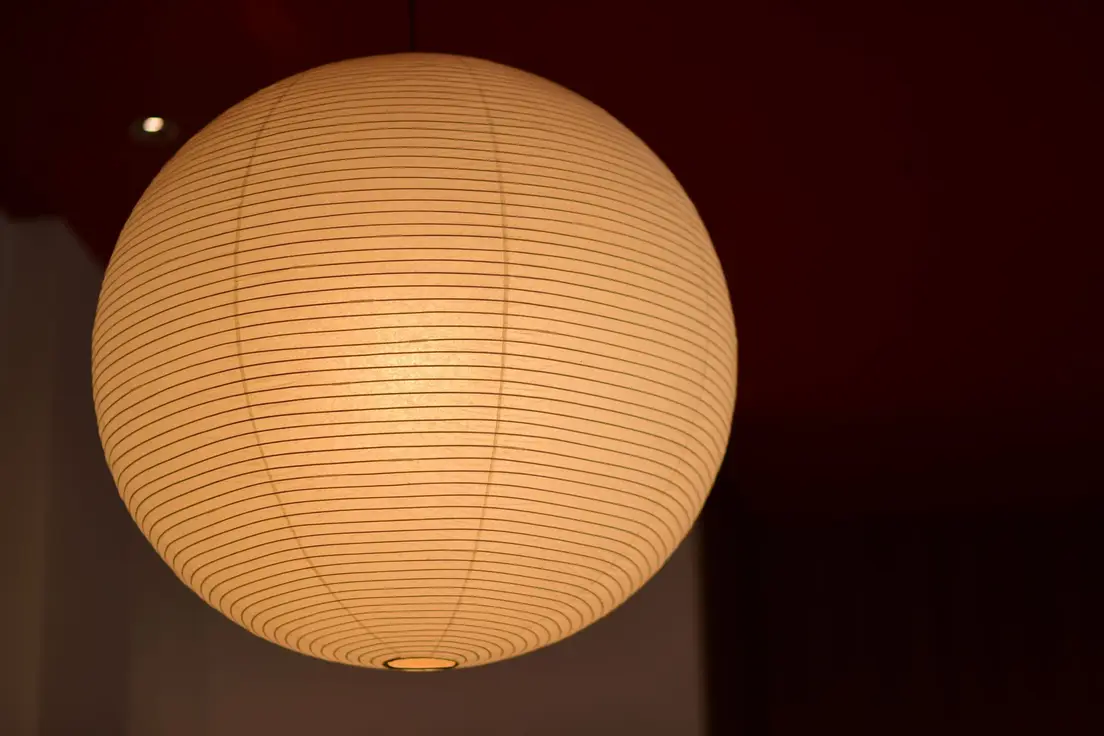 A glowing round paper lantern pendant light giving off warm 2700K-style light