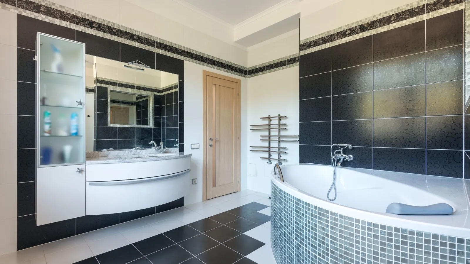 A bathroom with a black and white checkerboard tile floor, black patterned walls, and a mosaic-tiled tub