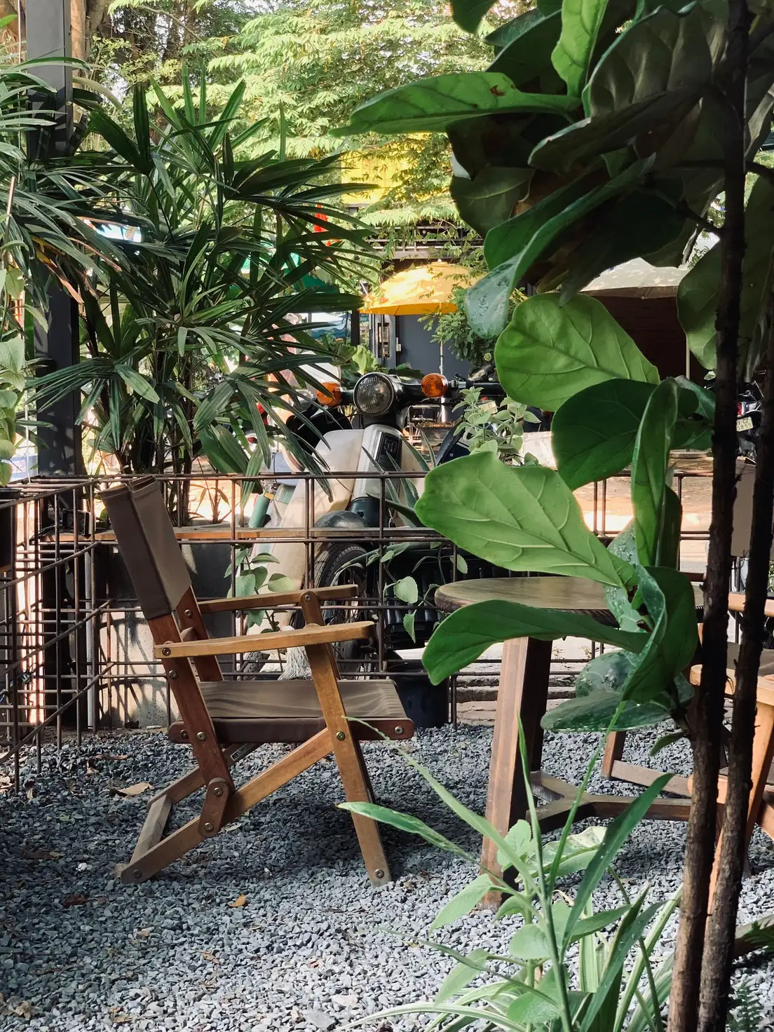 A small backyard patio covered in pea gravel with a simple folding chair and side table