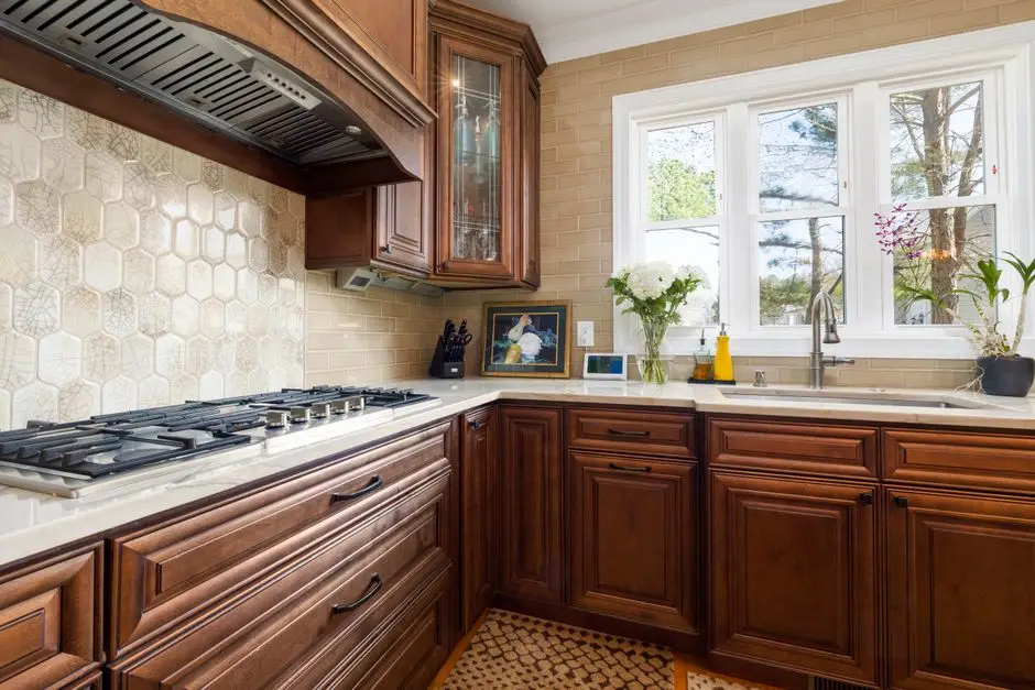 A hexagon-tile peel-and-stick backsplash installed above a kitchen counter and range