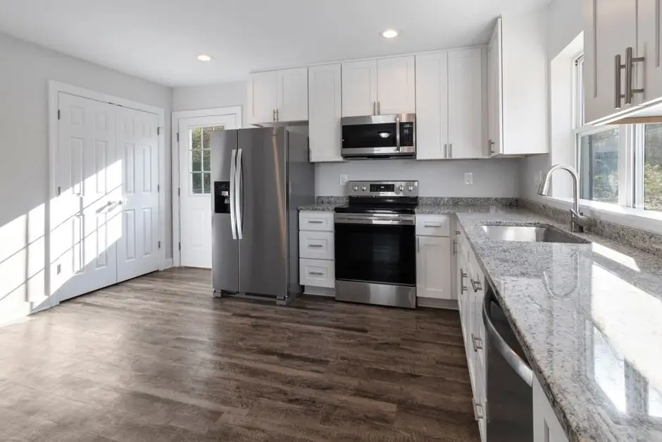 A small apartment kitchen with light wood-look vinyl flooring and white cabinetry