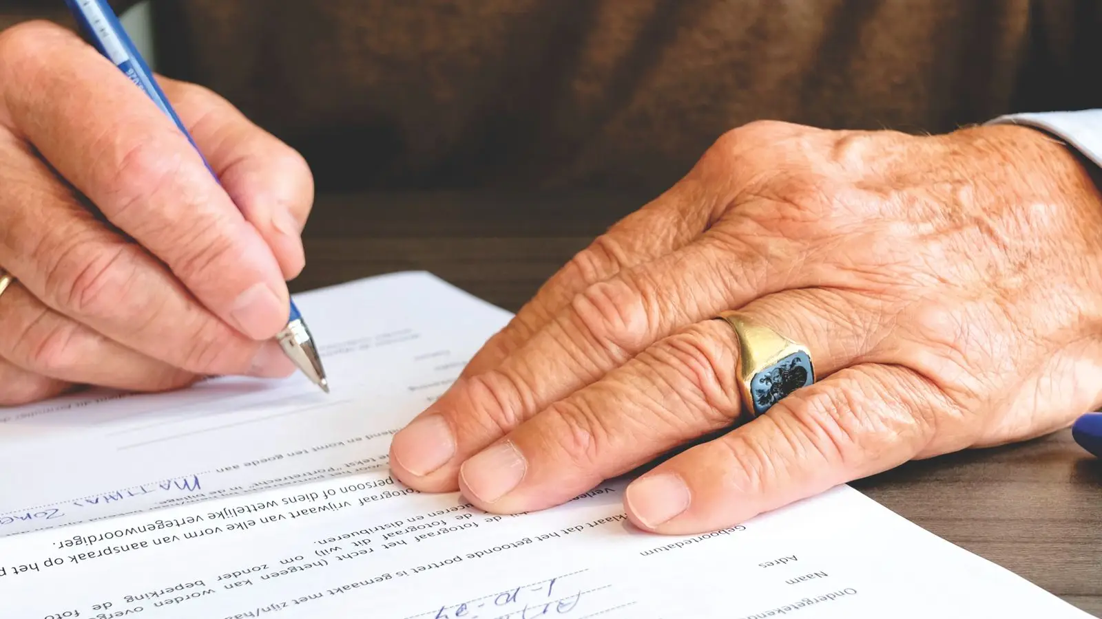 A hand signing a lease or building permit document, illustrating the check-before-you-build step for a temporary wall