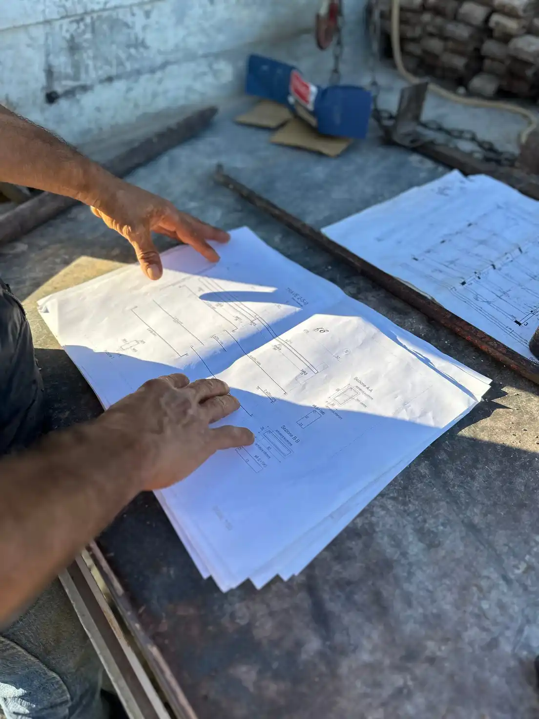 A pair of hands reviewing architectural blueprints for an outdoor building project