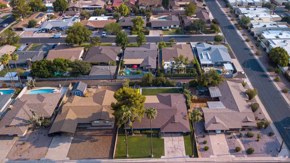 Aerial view of a postwar suburb of single-story ranch houses with low hip roofs, carports, and backyard pools