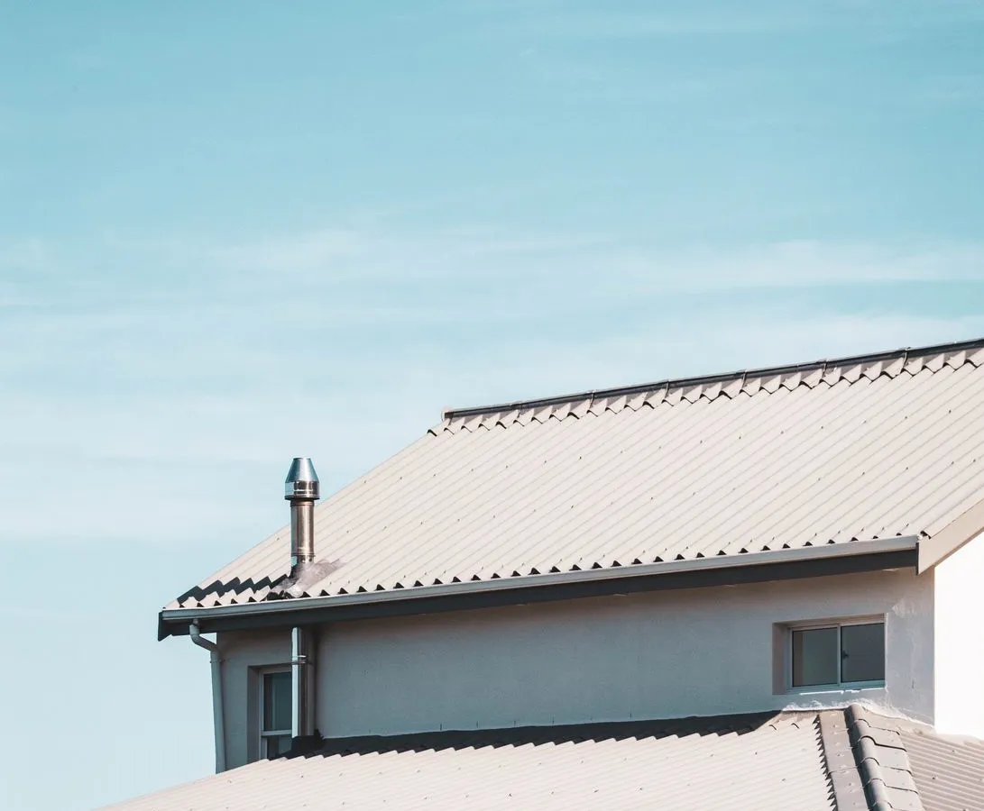 A close-up of a house roofline with tiled shingles and matching light-colored fascia trim