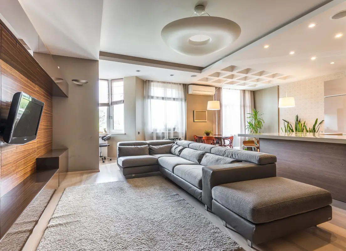A large area rug anchoring a sectional sofa's front legs in a living room