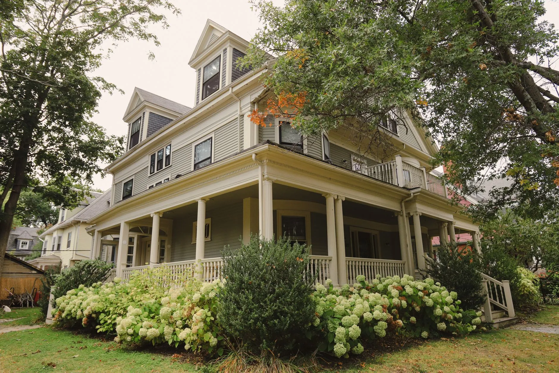A pulled-together white and greige farmhouse exterior with a front porch and foundation plantings