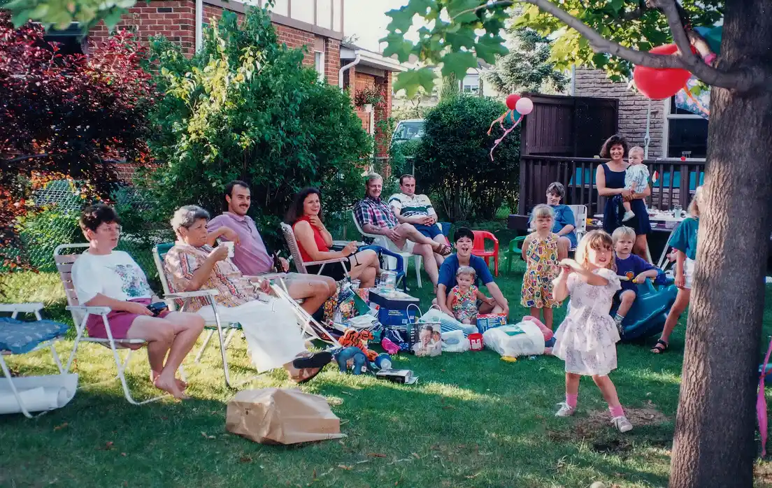 A large multi-generational backyard party with rows of lawn chairs for guests