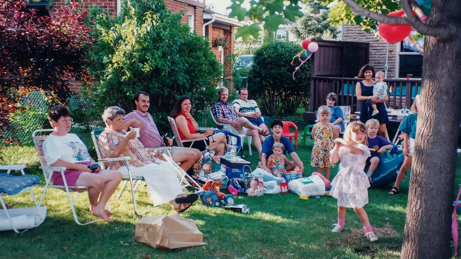 A large multi-generational backyard party with rows of lawn chairs for guests