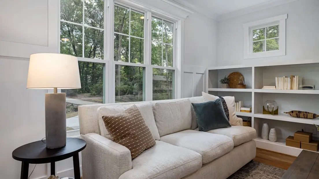 A bright, airy modern farmhouse sitting room with built-in shelving and large windows