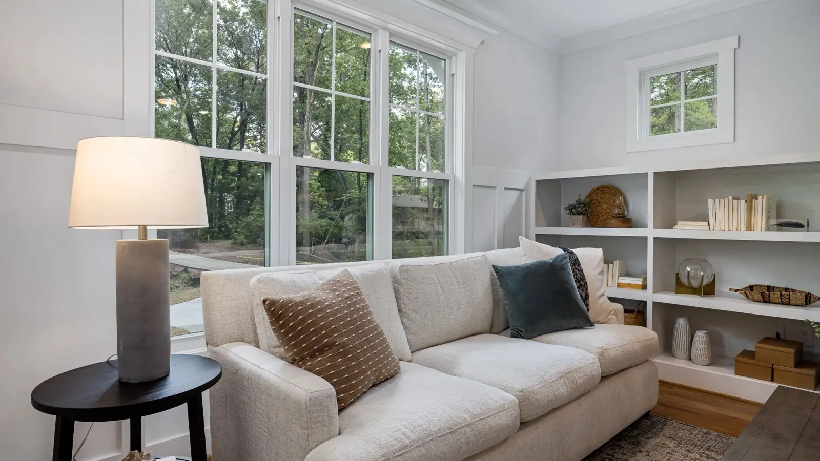 A bright, airy modern farmhouse sitting room with built-in shelving and large windows