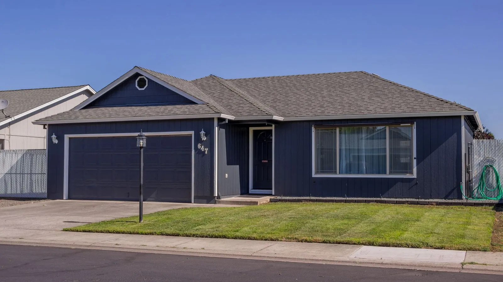 A navy single-story ranch house with a red front door, an example of finished curb appeal
