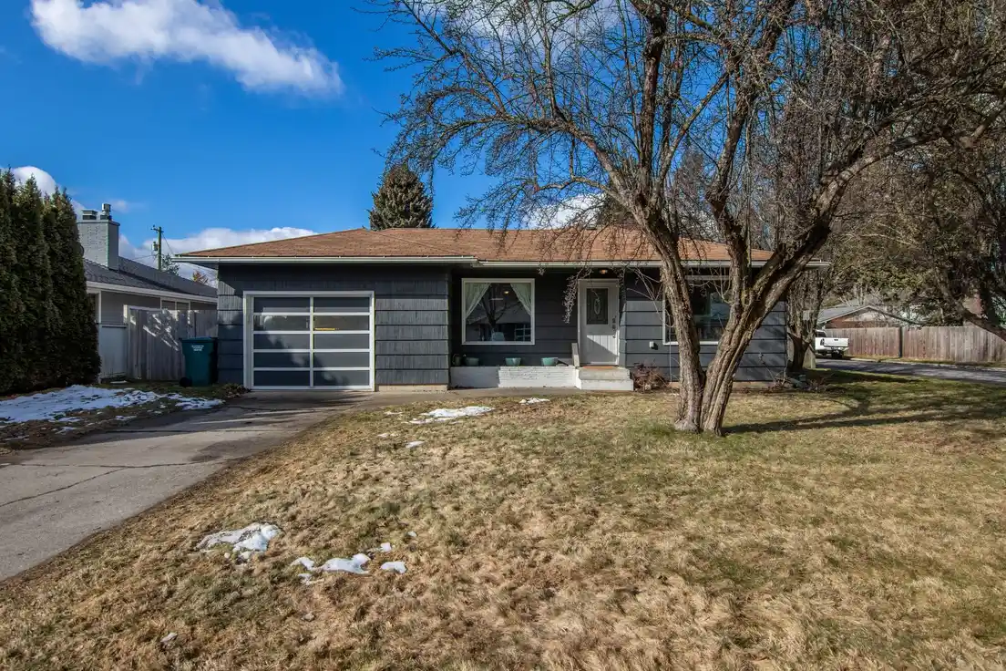 A finished ranch house exterior with an attached garage, brick and siding combination, and a walkway