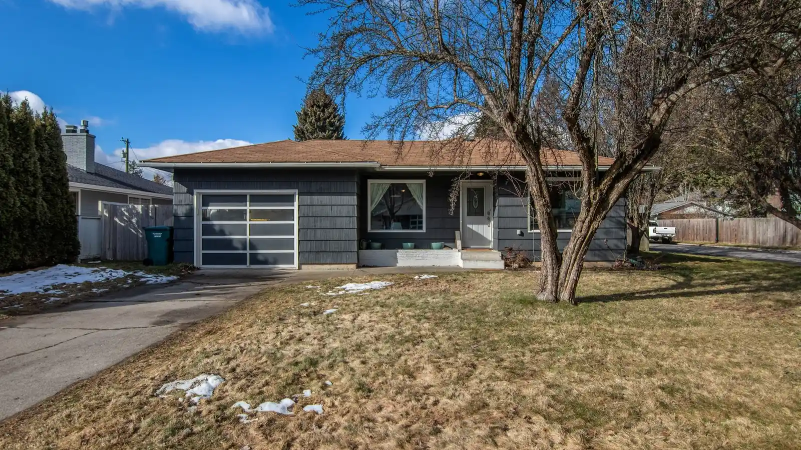 A finished ranch house exterior with an attached garage, brick and siding combination, and a walkway