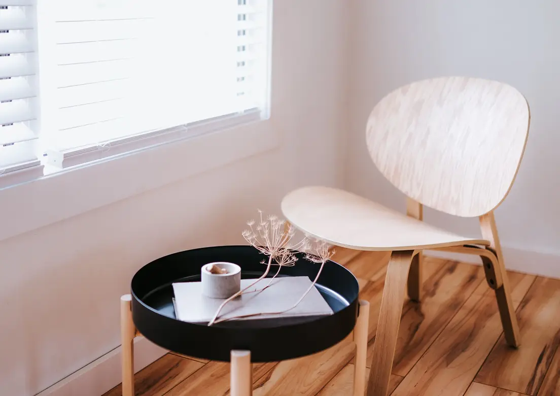 A light wood Scandinavian-style chair and round side table in a minimalist room