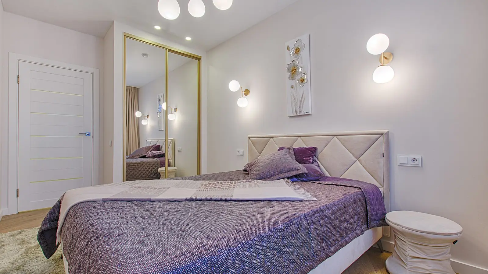 Two wall sconces flanking a bed on either side of a headboard in a small bedroom