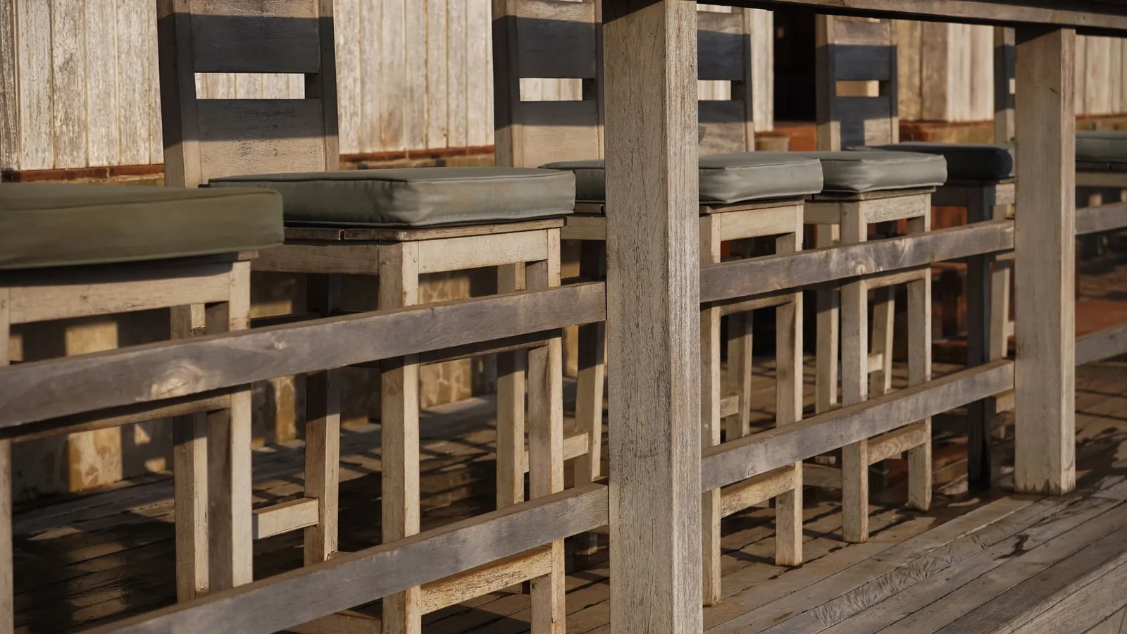 Rustic wooden bar stools along an outdoor counter in a backyard bbq area