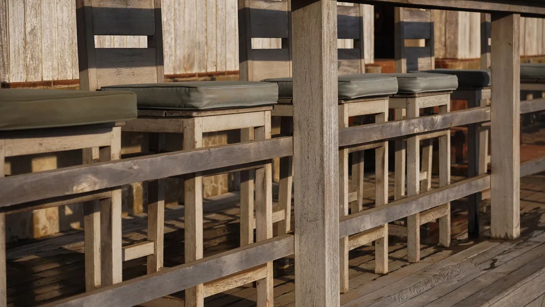 Rustic wooden bar stools along an outdoor counter in a backyard bbq area