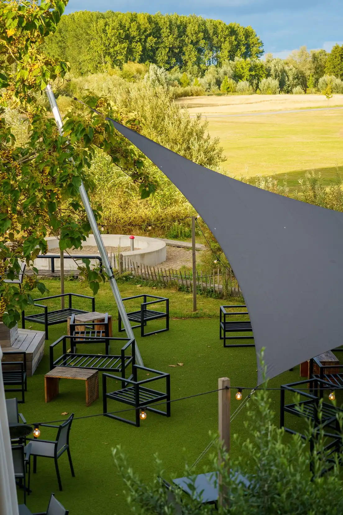 A gray triangular shade sail stretched over an outdoor seating area