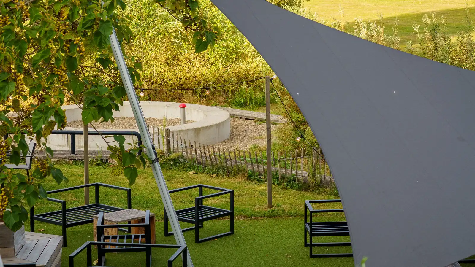 A gray triangular shade sail stretched over an outdoor seating area