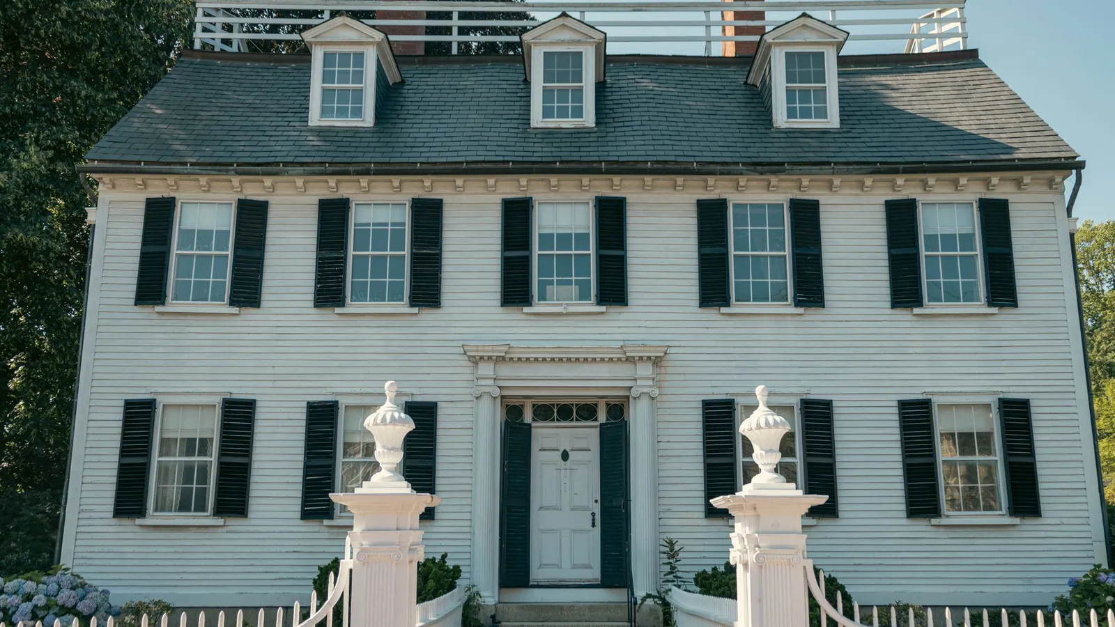 A white colonial house with matching black shutters repeated symmetrically across every window