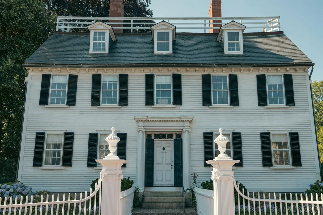 A white colonial house with matching black shutters repeated symmetrically across every window