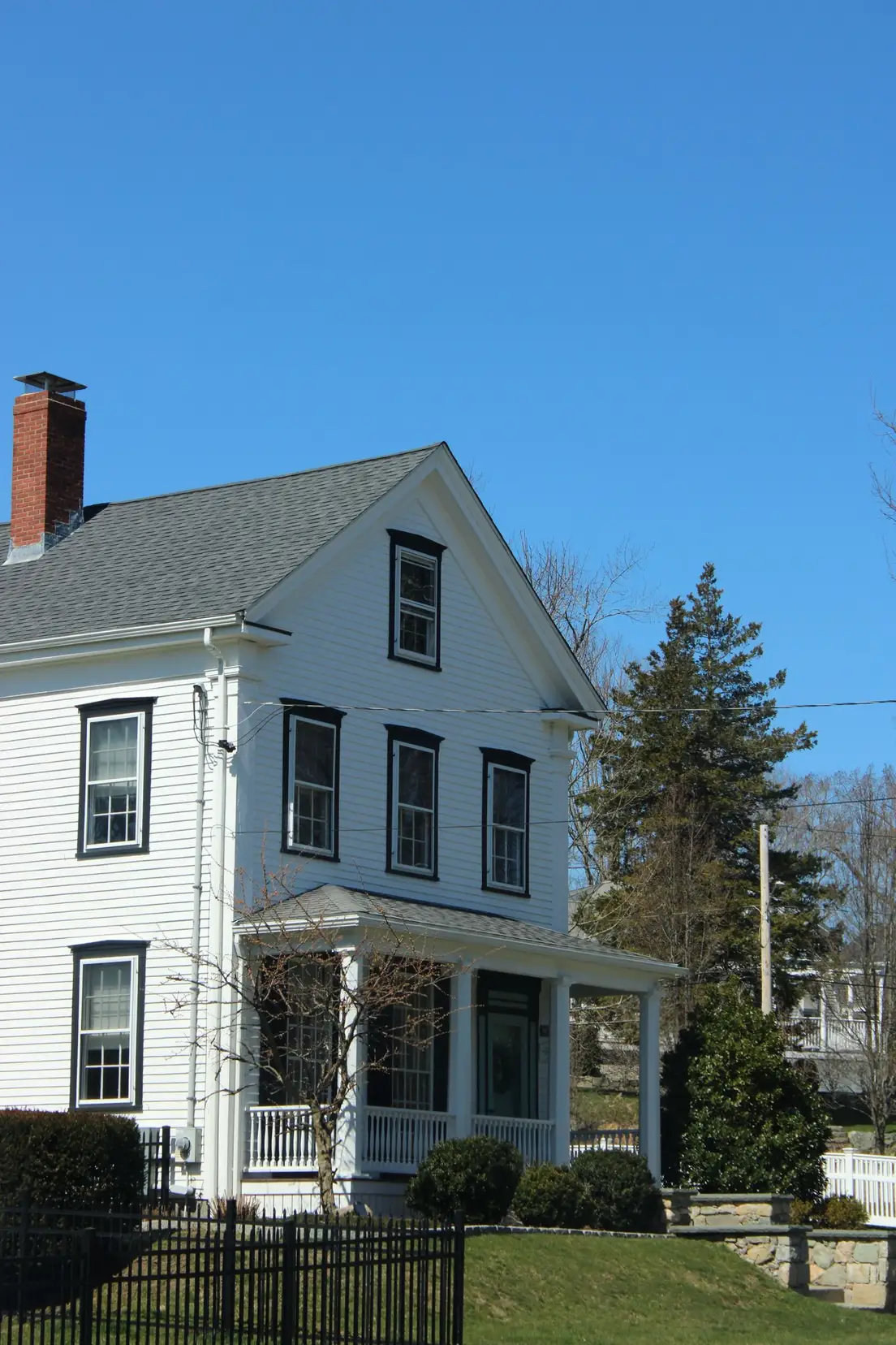A white New England colonial house with black shutters framing every window