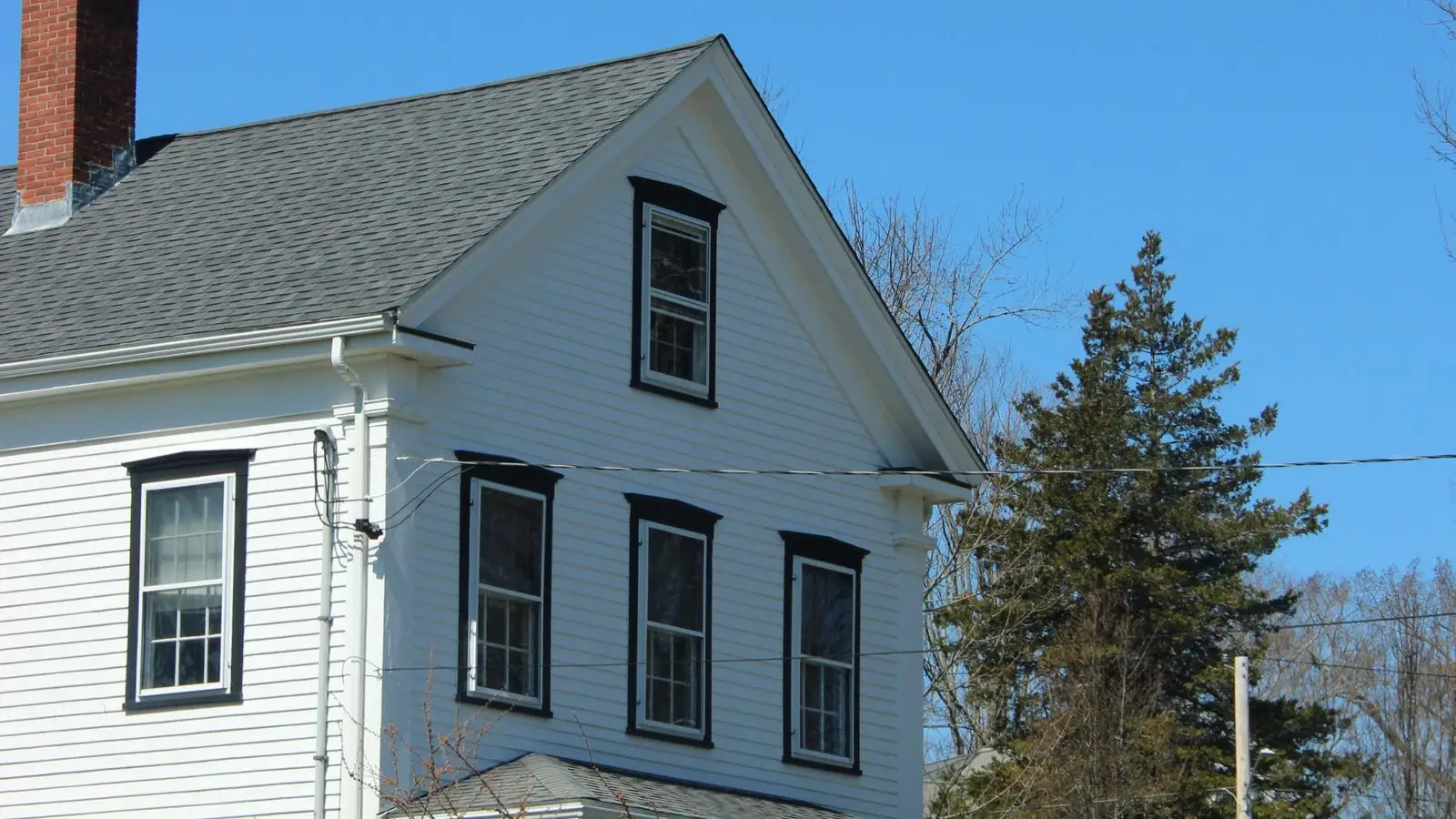 A white New England colonial house with black shutters framing every window