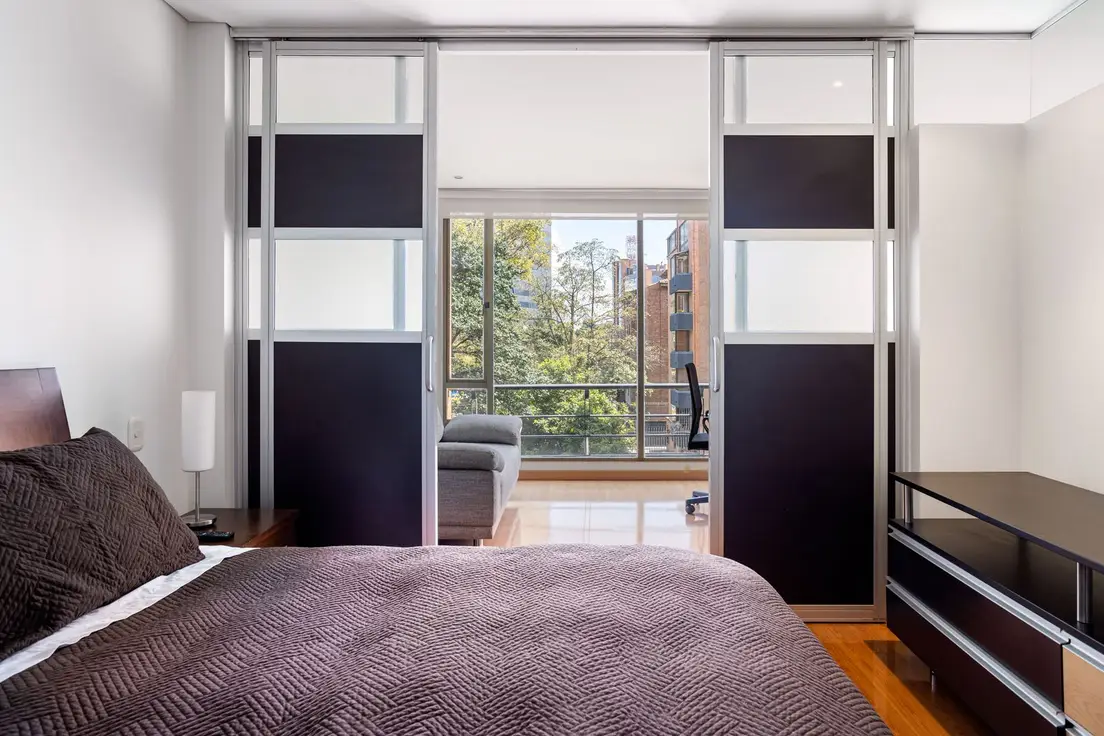 A minimalist bedroom with a sliding door room divider opening onto a living area