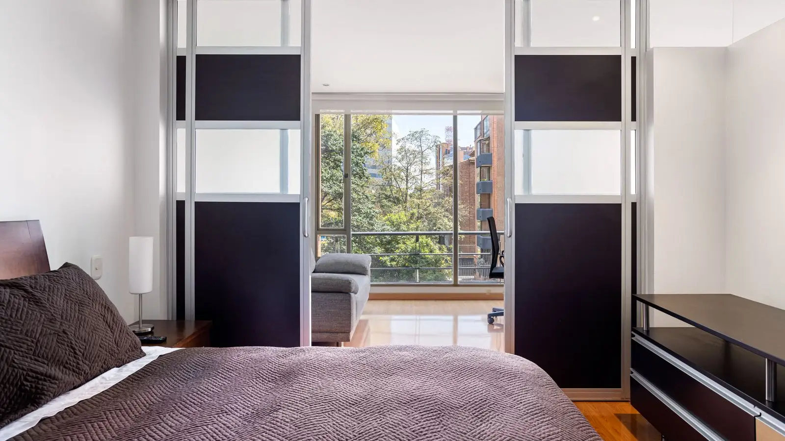 A minimalist bedroom with a sliding door room divider opening onto a living area