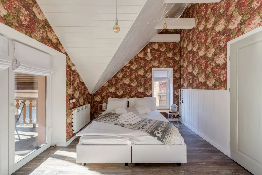 A primary bedroom with a sloped attic ceiling and furniture kept off the lowest wall