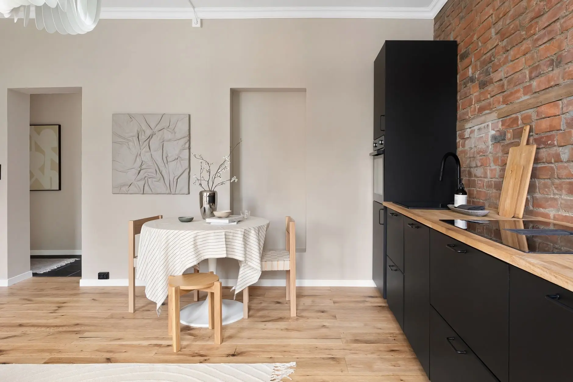 A small apartment kitchen nook with a round table, wood floor, and minimal styling